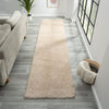 Beige modern shaggy runner rug on gray wood floor in bright hallway.