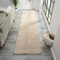 Beige modern shaggy runner rug on gray wood floor in bright hallway.