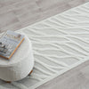 Ivory runner rug with raised geometric wave pattern and textured polypropylene pile on light wood floor.