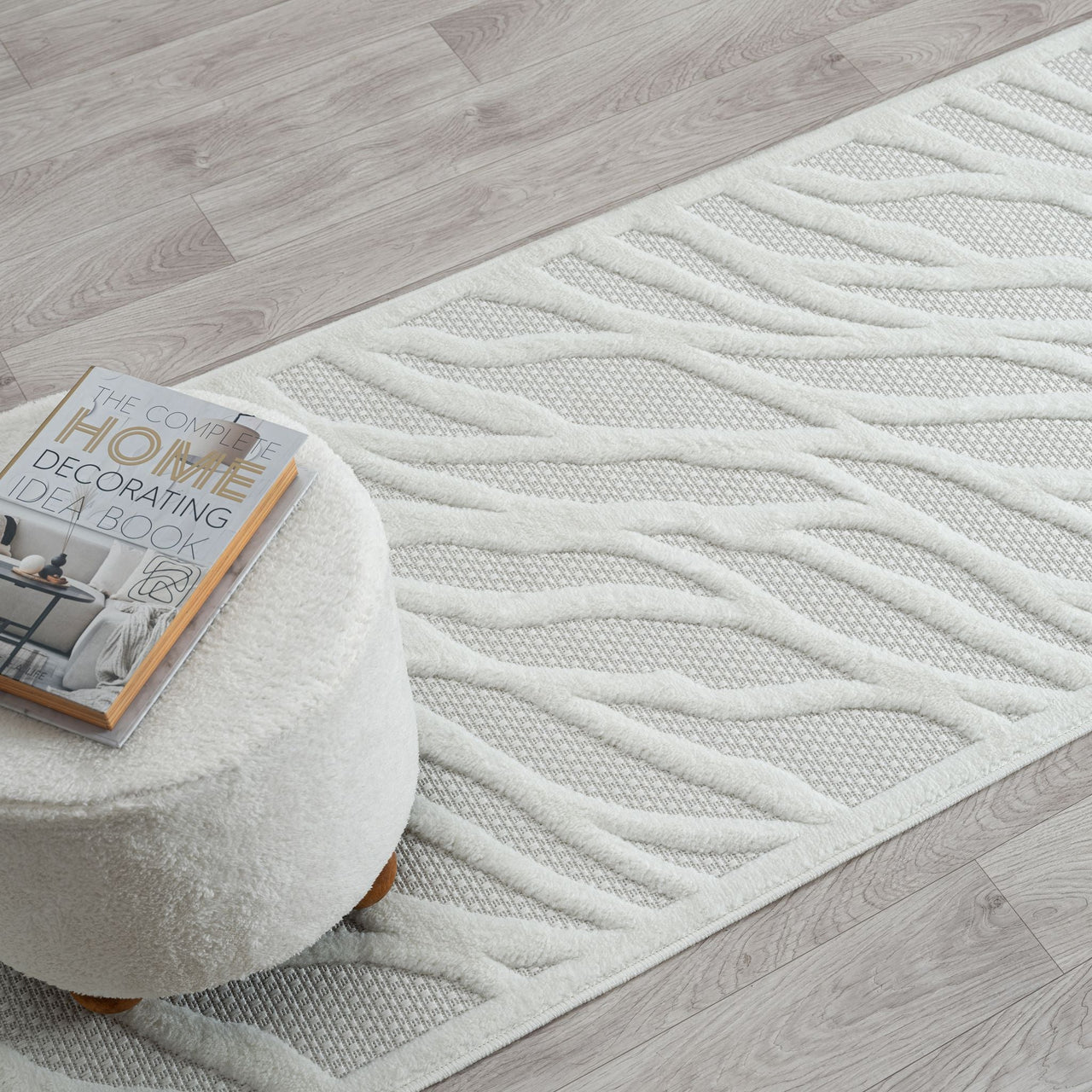 Ivory runner rug with raised geometric wave pattern and textured polypropylene pile on light wood floor.