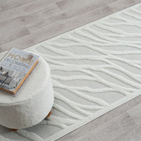 Ivory runner rug with raised geometric wave pattern and textured polypropylene pile on light wood floor.