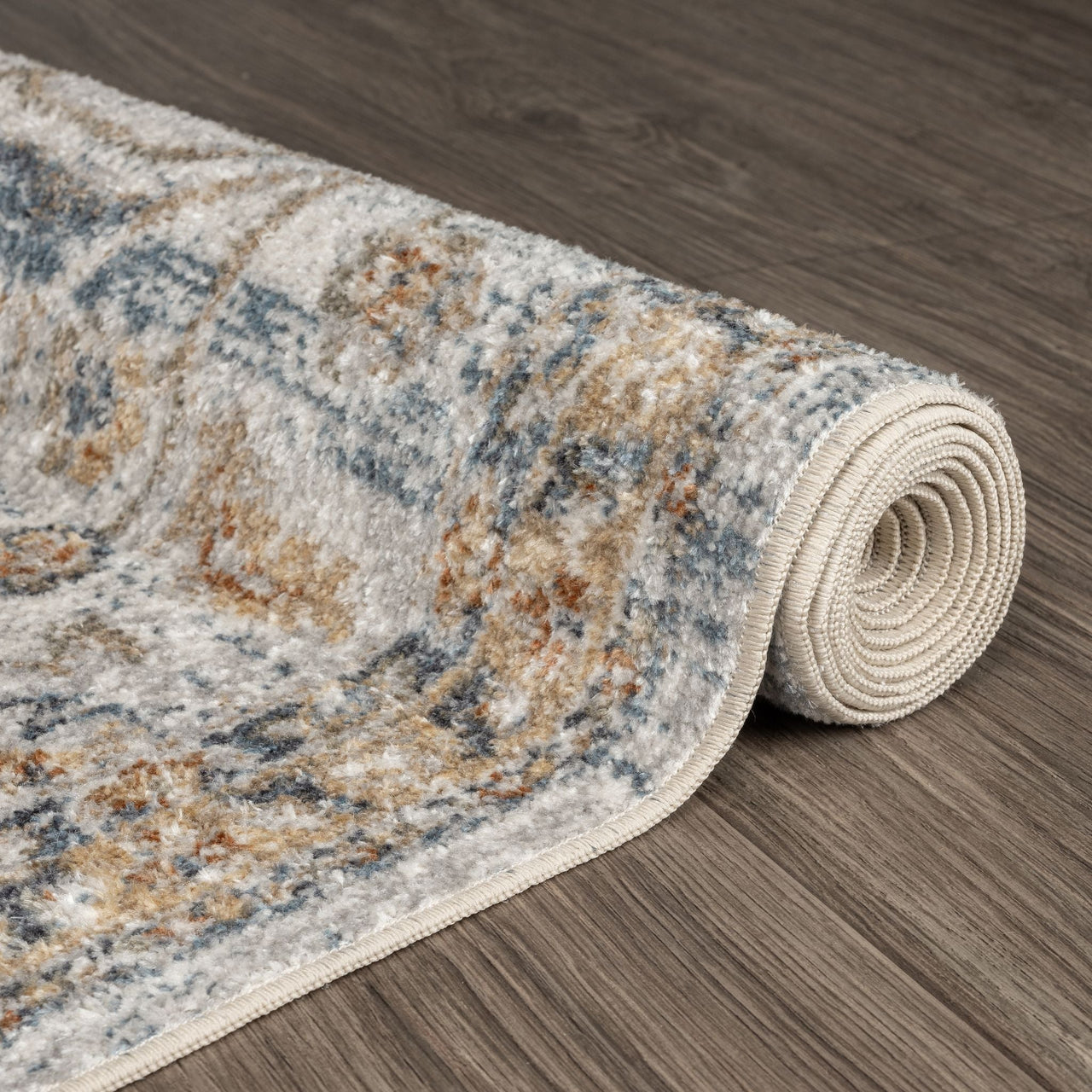 Rolled modern runner rug in muted blue, beige, and brown with a distressed, transitional pattern on wood floor.