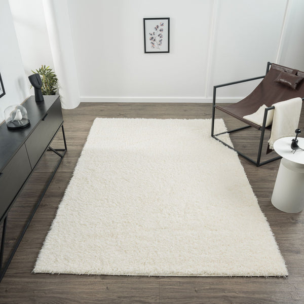 Cream modern shaggy rug with thick polyester pile on wooden floor in minimalist living room setting.