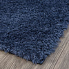Navy blue modern shaggy rug corner on wooden floor with dense polyester fibers.