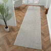Grey flatweave runner rug with subtle linear geometric pattern on wood parquet floor.