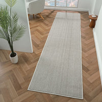 Grey flatweave runner rug with subtle linear geometric pattern on wood parquet floor.