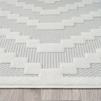Cream and beige geometric patterned rug with textured polypropylene pile on wood floor.