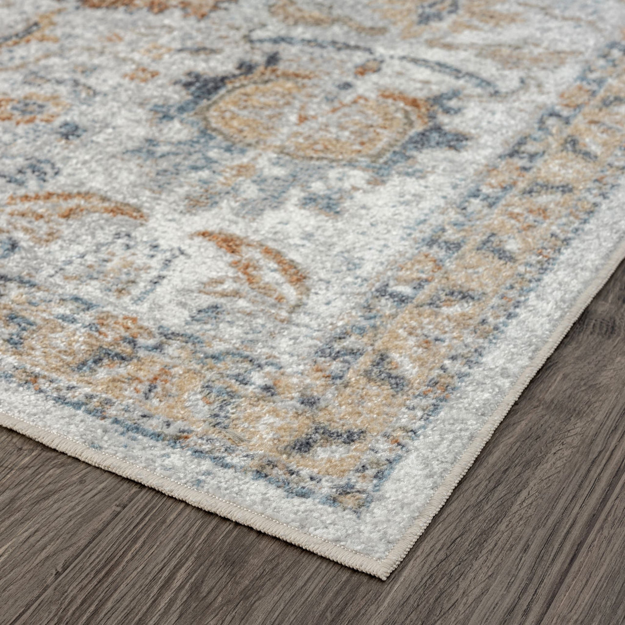 Close-up of a muted multi-colored runner rug with soft blue, beige, and rust tones and intricate traditional patterns on a.