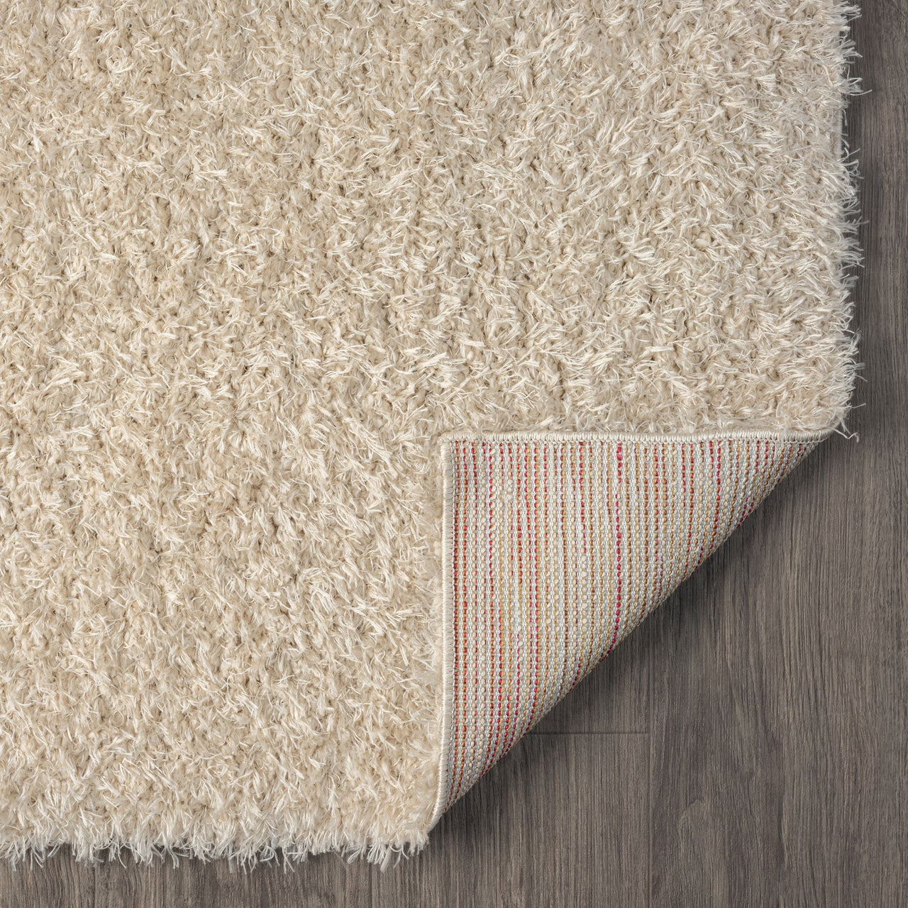 Beige modern shaggy runner rug with thick polyester fibers and rounded corners, corner folded to show striped backing on.