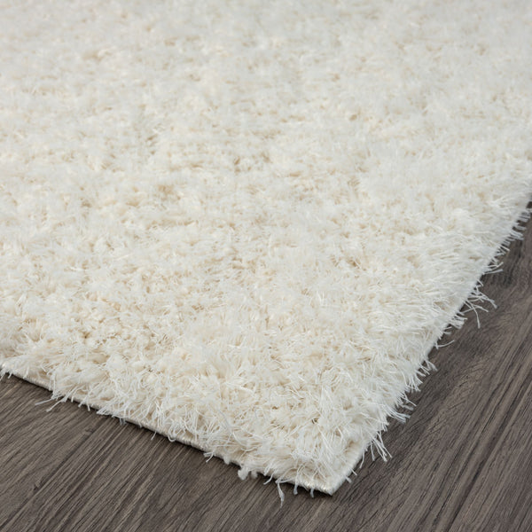 Cream-colored modern shaggy rug with thick, plush polyester fibers on dark wood floor.