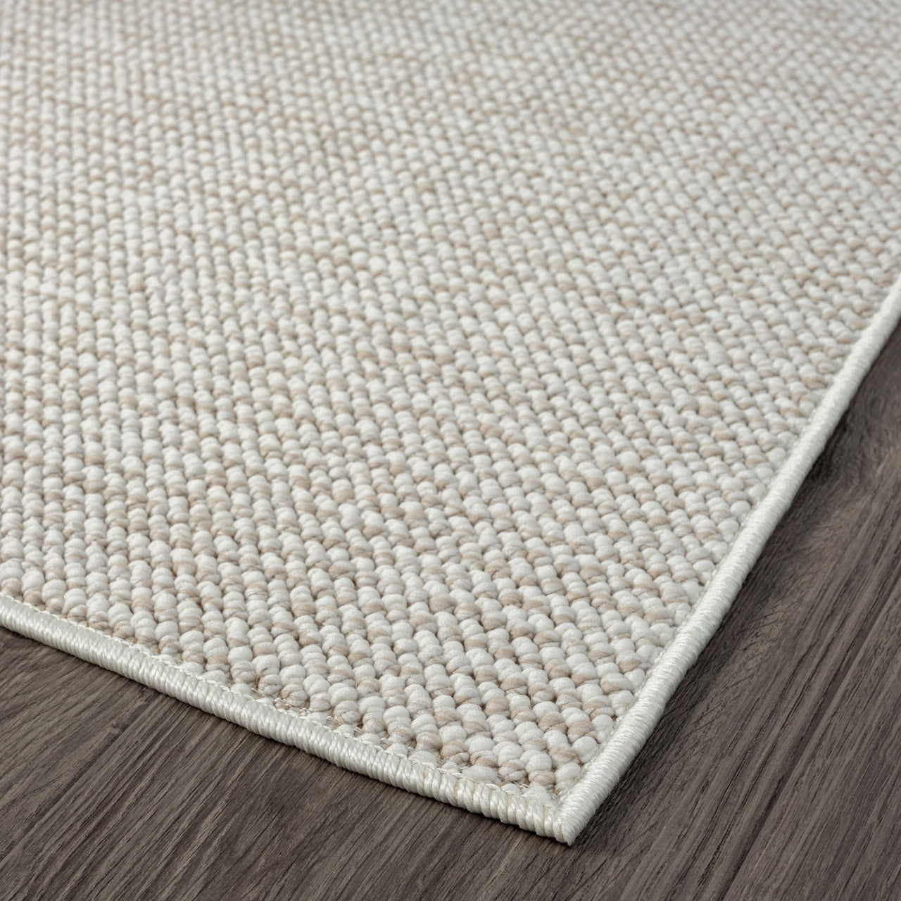 Beige flatweave rug with a subtle textured geometric pattern and clean edge on dark hardwood floor.