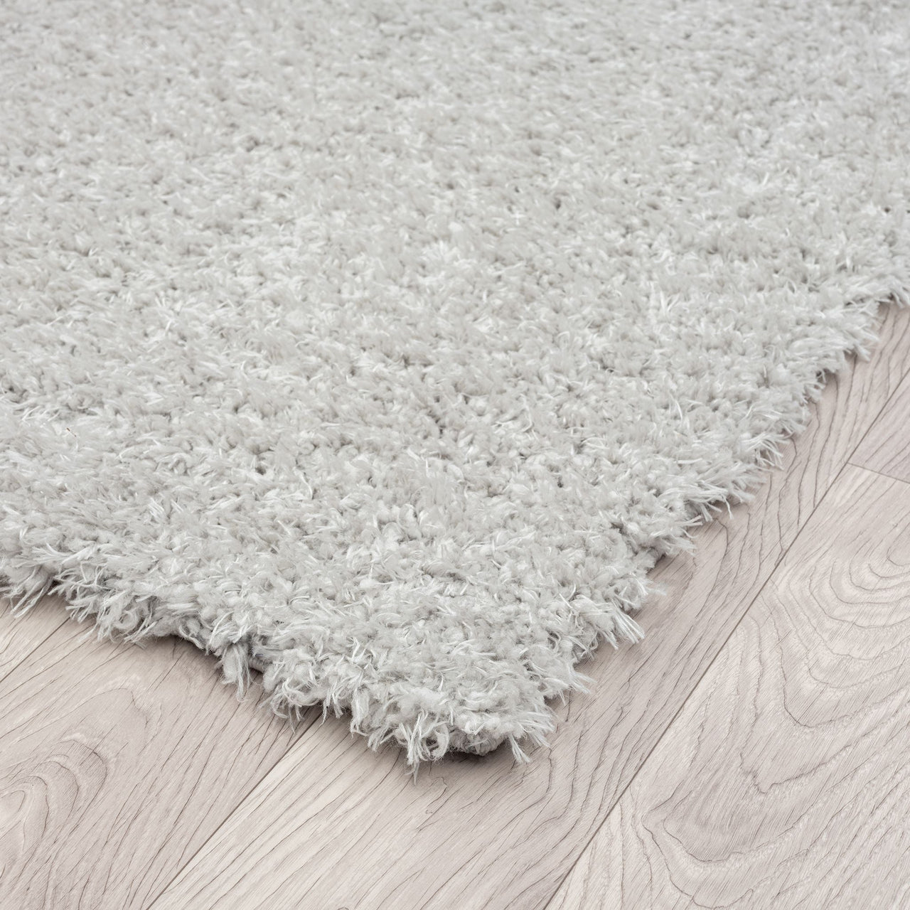 Light grey shaggy runner rug with thick polyester pile on light wood floor.