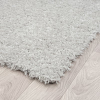 Light grey shaggy runner rug with thick polyester pile on light wood floor.