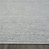 Grey flatweave rug with subtle geometric texture and low pile on wooden floor.
