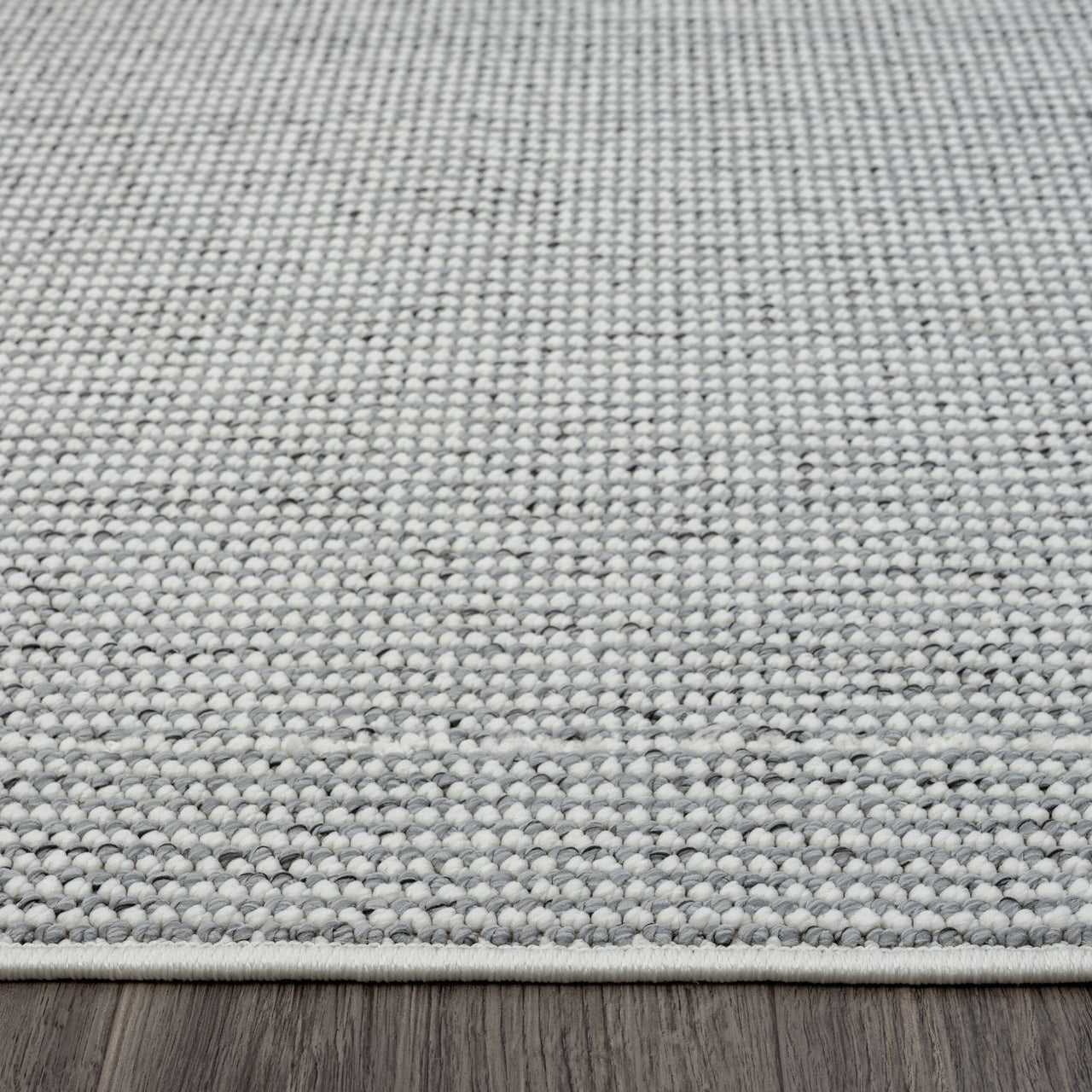 Grey flatweave rug with subtle geometric texture and low pile on wooden floor.