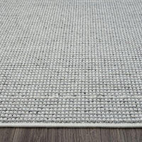 Grey flatweave rug with subtle geometric texture and low pile on wooden floor.