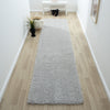 Grey modern shaggy runner rug with plush texture on light wood hallway floor.