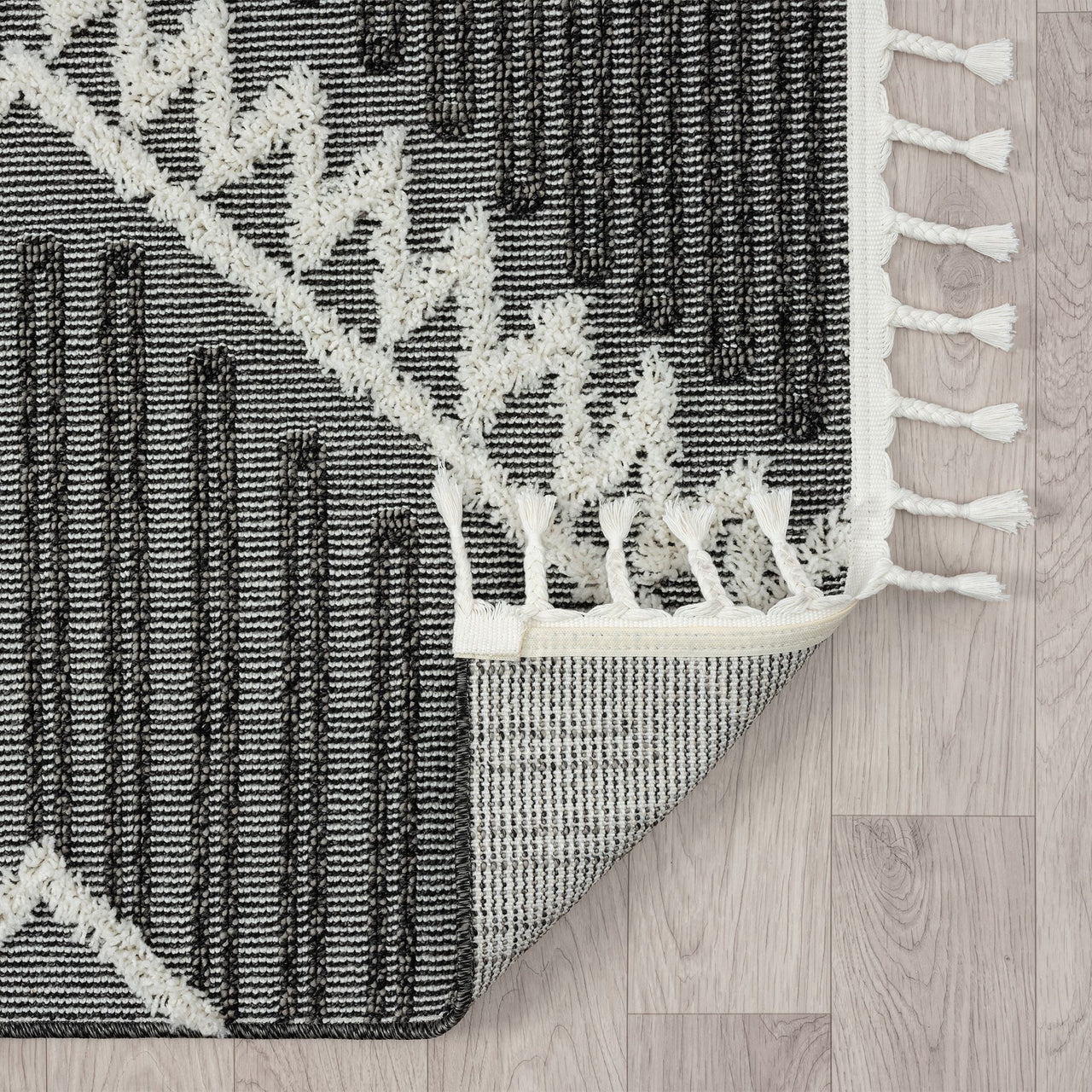 Grey and white runner rug with modern geometric pattern and fringed edges on light wood floor.