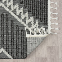 Grey and white runner rug with modern geometric pattern and fringed edges on light wood floor.