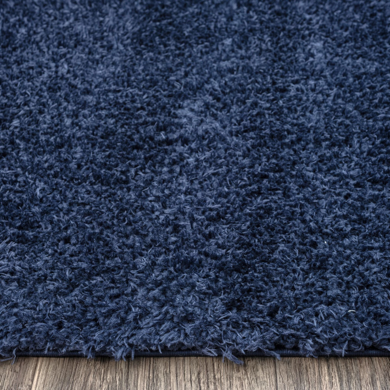 Navy blue modern shaggy rug with plush polyester fibers on wooden floor.