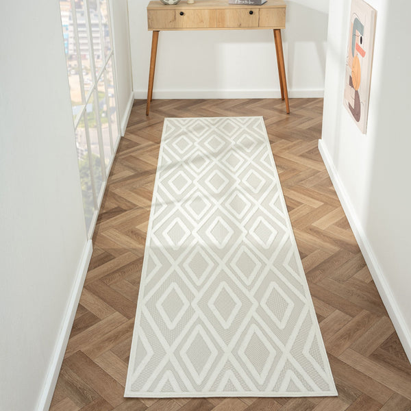 Grey and white geometric patterned modern runner rug on wood parquet floor.