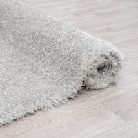 Light grey modern shaggy runner rug with dense, plush polyester fibers on light wood floor.