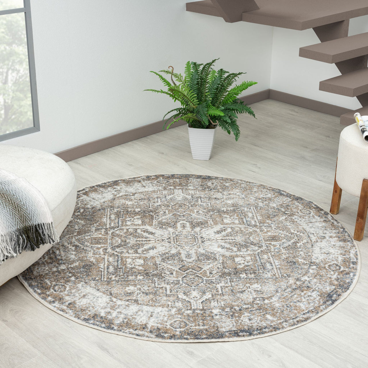 Round multi-colored rug with intricate geometric patterns in neutral tones on light wood floor.