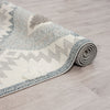Rolled grey and cream runner rug with textured geometric zigzag and dotted patterns, fringed ends.
