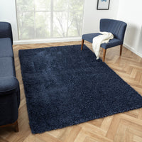 Navy blue modern shaggy rug with plush texture on light wood herringbone floor.