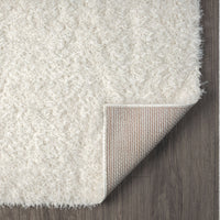 Cream shaggy runner rug with thick polyester fibers and a flexible backing, shown on dark hardwood floor.