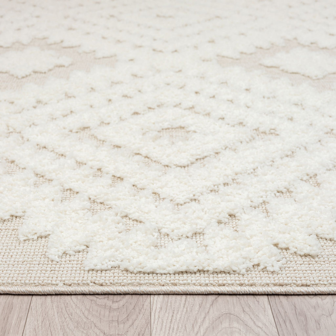 Beige and white runner rug with textured geometric diamond pattern and fringed edges on wood floor.