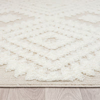 Beige and white runner rug with textured geometric diamond pattern and fringed edges on wood floor.