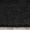 Black modern shaggy runner rug with dense plush texture on wooden floor.
