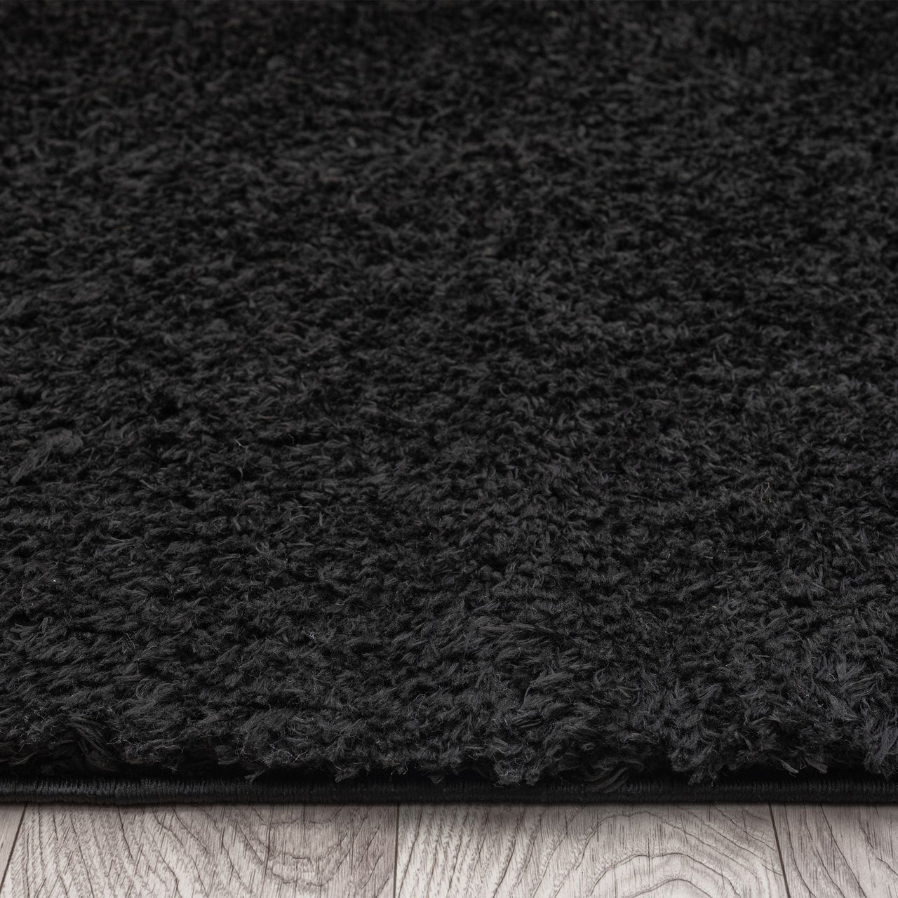 Black modern shaggy runner rug with dense plush texture on wooden floor.