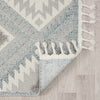 Grey and cream geometric patterned runner rug with fringed edges on light wood floor.