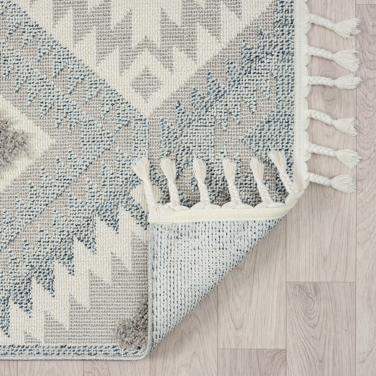 Grey and cream geometric patterned runner rug with fringed edges on light wood floor.