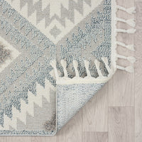 Grey and cream geometric patterned runner rug with fringed edges on light wood floor.