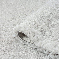 Soft grey shaggy runner rug with thick plush pile and textured backing visible on curled edge.