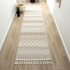 Beige and cream runner rug with modern geometric patterns and fringe edges on light wood floor hallway.