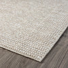 Taupe flatweave rug with subtle textured geometric pattern on dark wood floor.