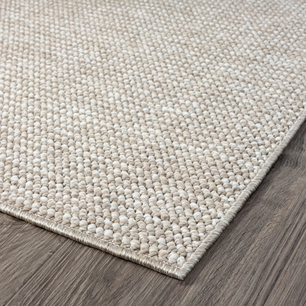 Taupe flatweave rug with subtle textured geometric pattern on dark wood floor.