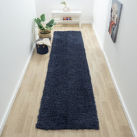 Navy blue modern shaggy runner rug on light wood floor in narrow hallway.