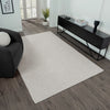 Beige flatweave rug with subtle texture on dark wood floor in modern living room setting.