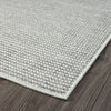Close-up of a silver grey flatweave rug corner with a subtle textured pattern on dark wood floor.