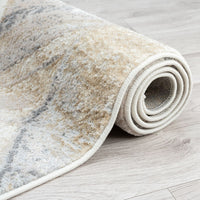 Rolled-up beige and gray patterned rug on a light wooden floor.