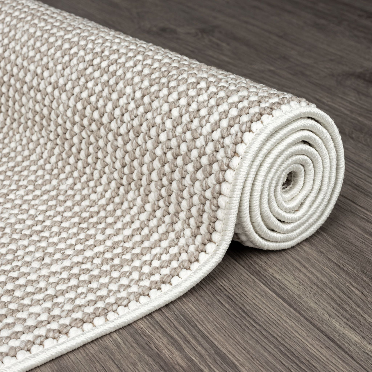 Rolled beige and cream flatweave runner rug with textured geometric pattern on wood floor.