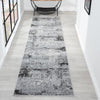 Long, narrow runner rug with a gray and black pattern on a light wooden floor.
