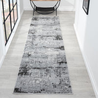 Long, narrow runner rug with a gray and black pattern on a light wooden floor.