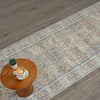 Long coral runner rug with intricate floral and geometric patterns in muted tones on wood floor.