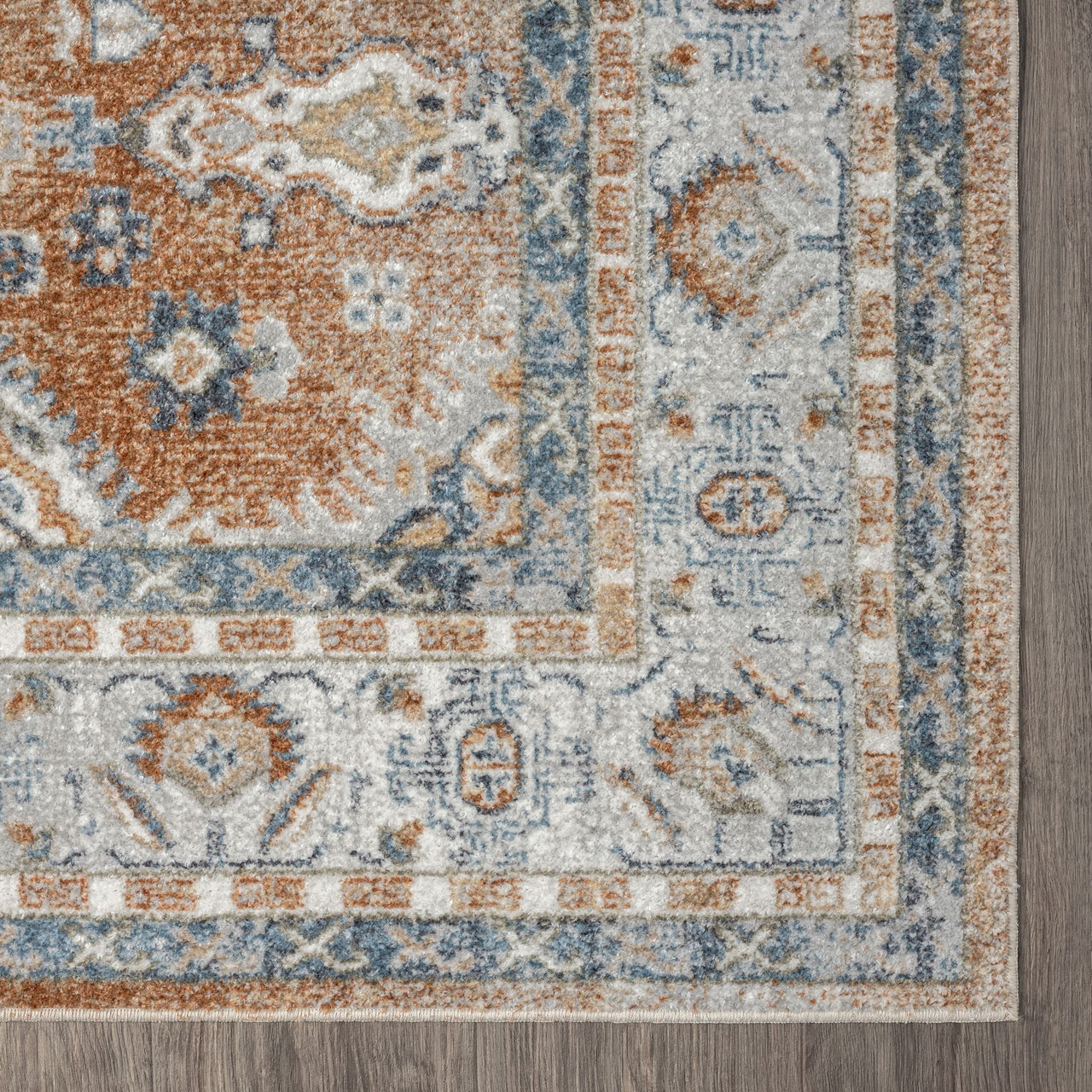Rectangular rug corner with a traditional floral pattern in muted blue, rust, beige, and cream tones.